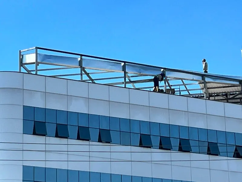 Montadores trabalhando na estrutura da cobertura, no alto do prédio