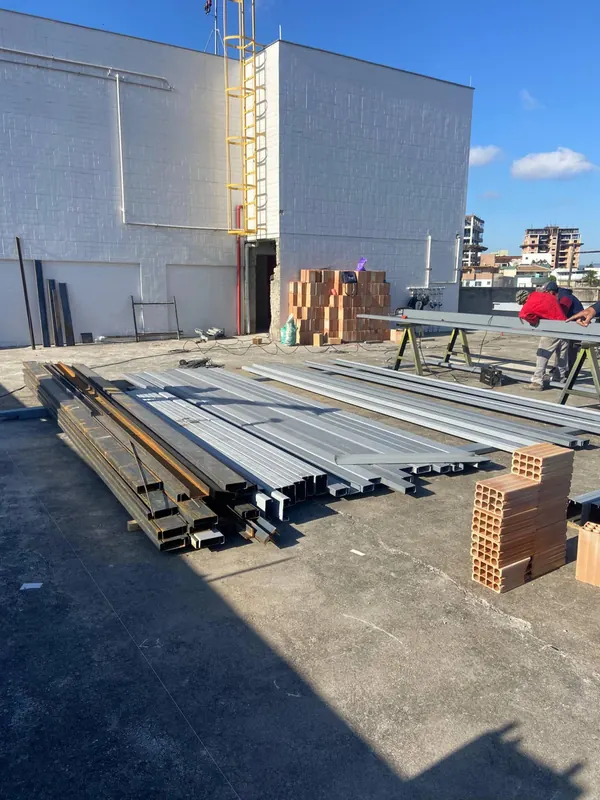 Perfis metálicos e materiais estocados na laje para a montagem