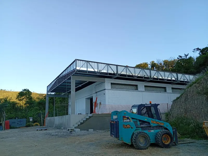 Depósito com a estrutura da cobertura montada e o fechamento lateral em instalação