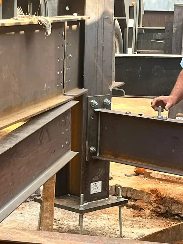 Viga sendo aparafusada ao pilar sobre a placa de base e os chumbadores