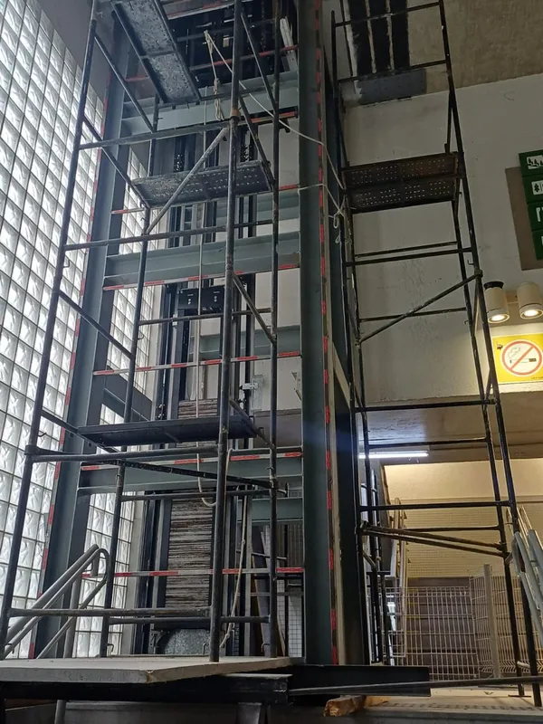 Estrutura da torre com as guias do elevador, cercada por andaimes