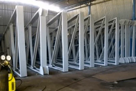 Peças de estrutura metálica pintadas e alinhadas na fábrica