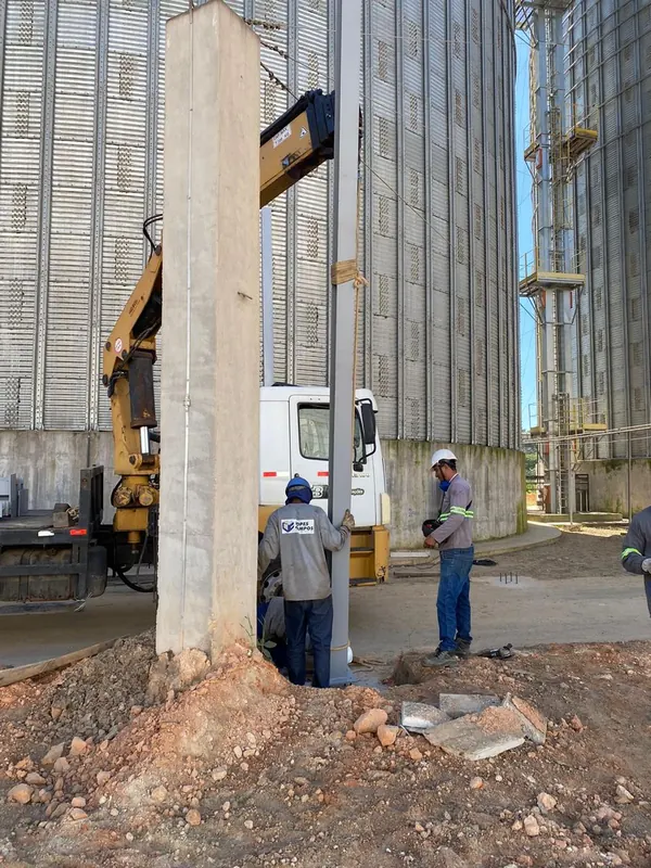 Pilar metálico sendo posicionado com caminhão munck ao lado dos silos