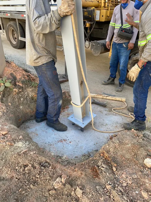 Equipe fixando a placa de base do pilar metálico na fundação