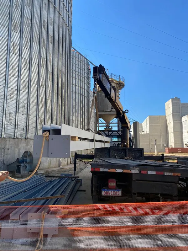 Perfis metálicos sendo descarregados pelo caminhão munck junto aos silos