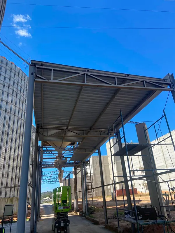 Cobertura metálica em montagem, vista de baixo contra o céu