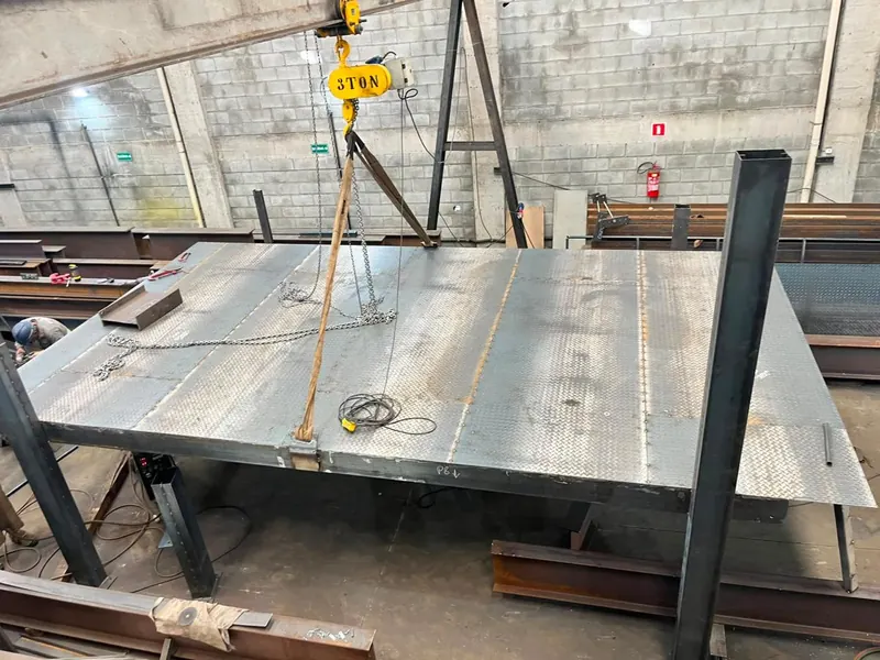 Plataforma de chapa xadrez sendo içada por talha na fábrica